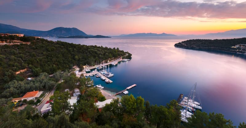 Sunset in sky and reflection in sea over coast in Greece.